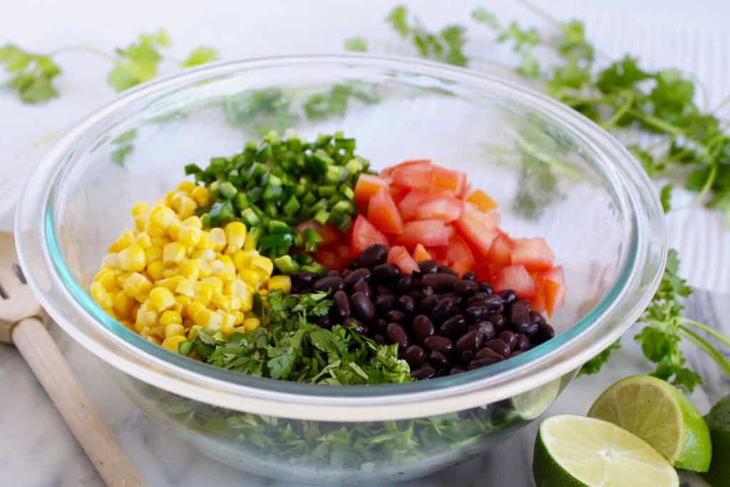 Black beans, corn, tomato and herbs in glass bowl.