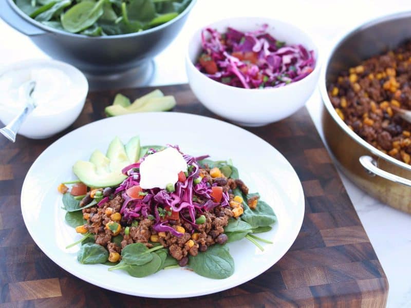 Taco salad on white plate on brown cutting board.