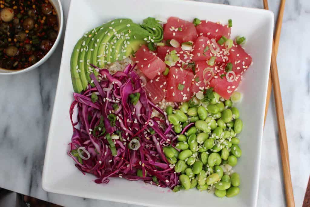 Raw tuna, edamame, avocado and cabbage in white bowl.