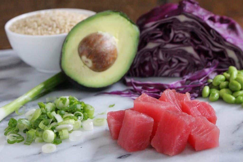 Raw tuna and vegetables on marble surface.