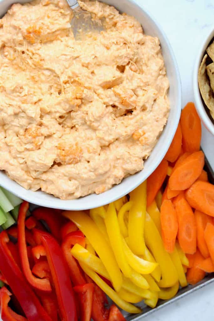 Buffalo dip in white bowl with sliced vegetables.