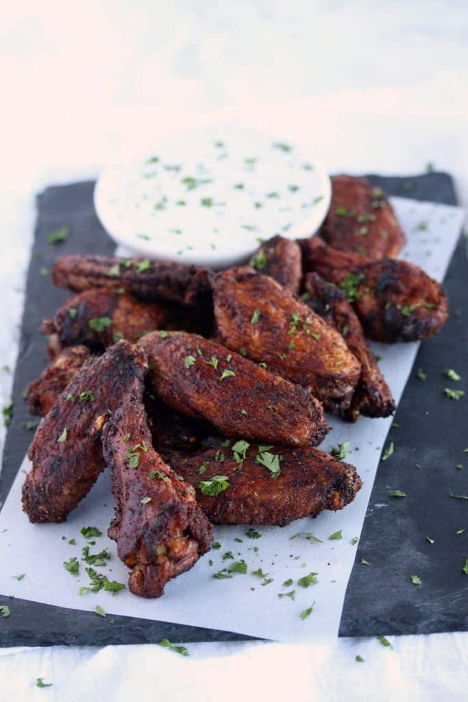 Crispy wings on blue serving platter with dip.