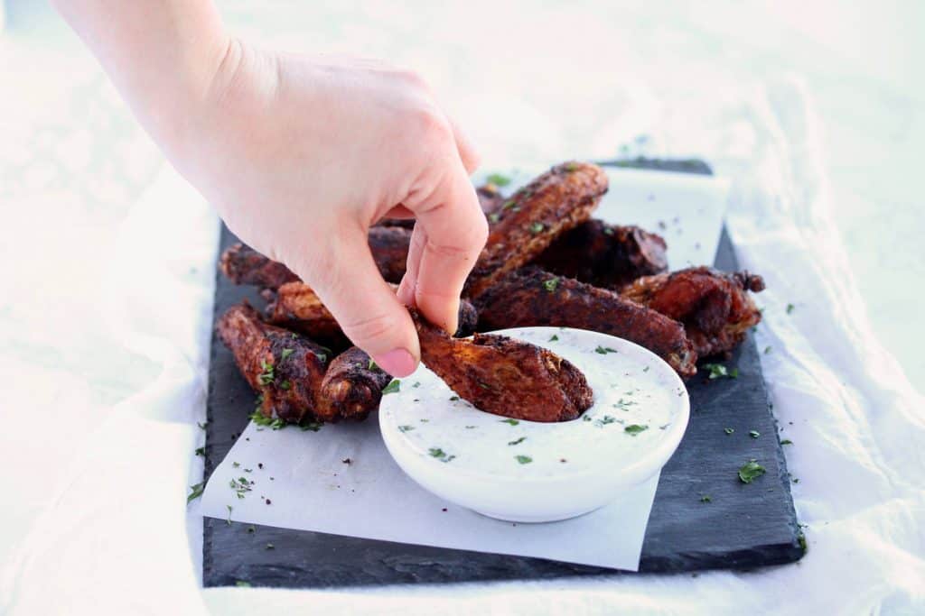 Crispy wings on blue serving platter with dip.