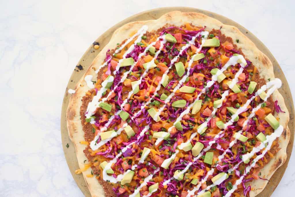 Colorful pizza on white surface.