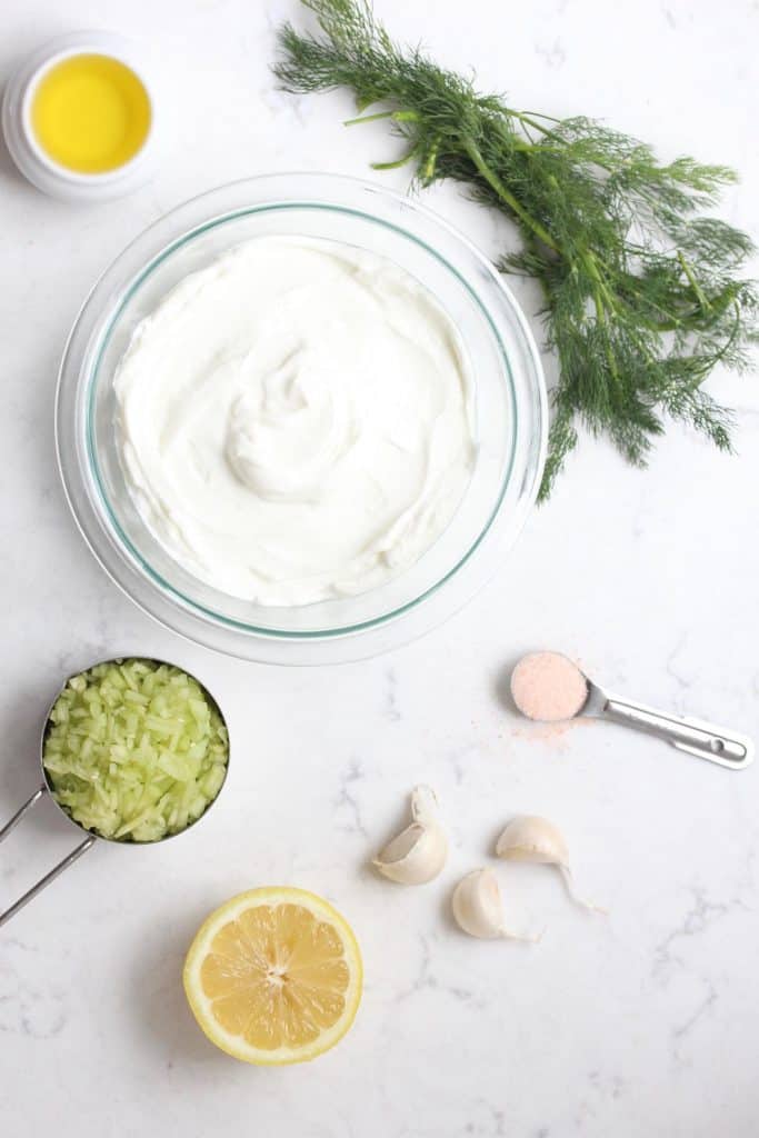 Yogurt, cucumber, lemon dill and garlic on marble surface.