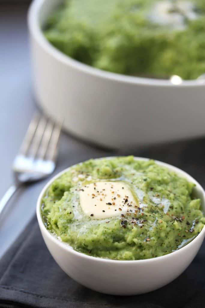 Spinach mashed potatoes in a white bowl on grey napkin.