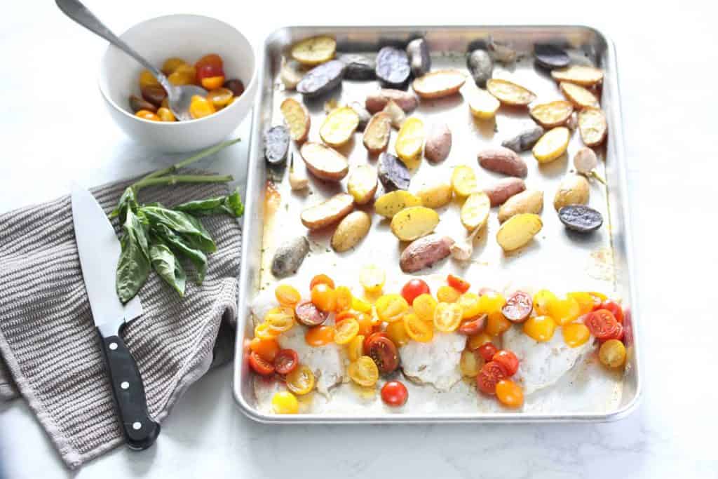 Chicken, tomatoes and baby potatoes on sheet pan.