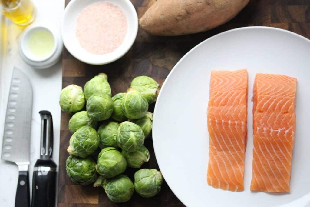 Salmon, sweet potatoes and Brussels sprouts on white plate.