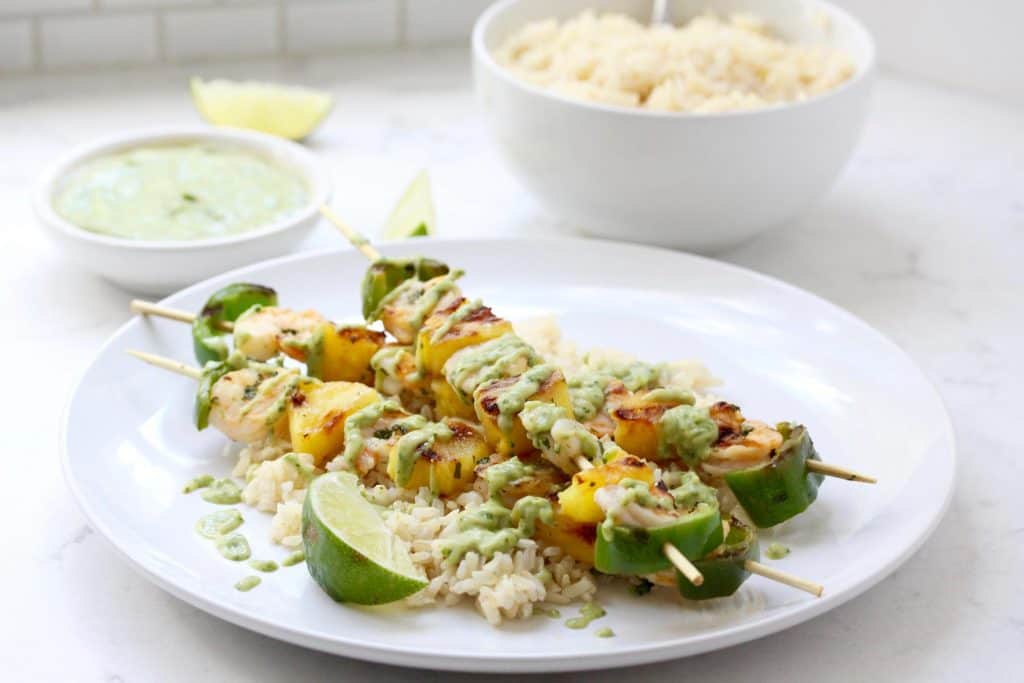 Shrimp skewers and rice on white plate.