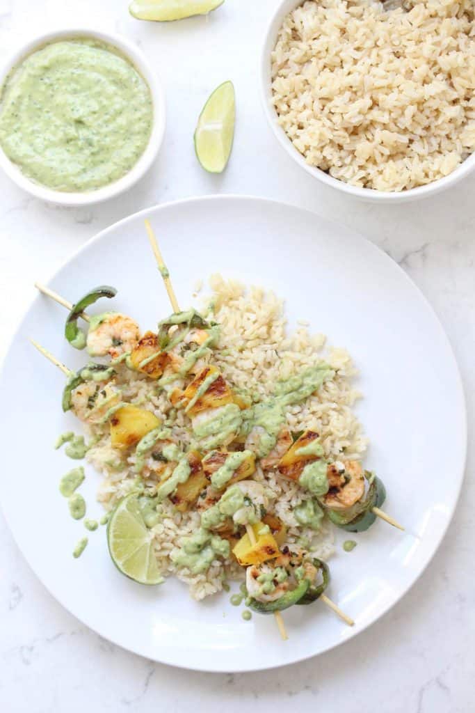 Shrimp skewers and rice on white plate.