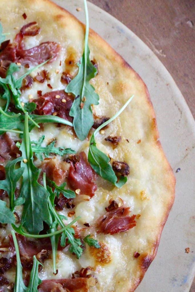 Flatbread on pizza stone on wood surface.