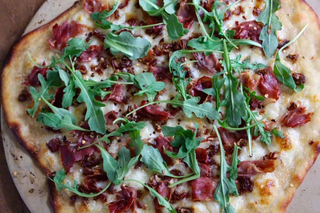 Flatbread on pizza stone on wood surface.