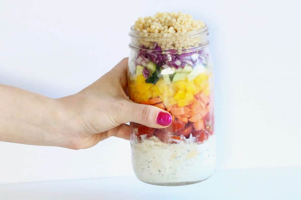 Fresh veggies, couscous and chicken in mason jar with Tzatziki sauce.