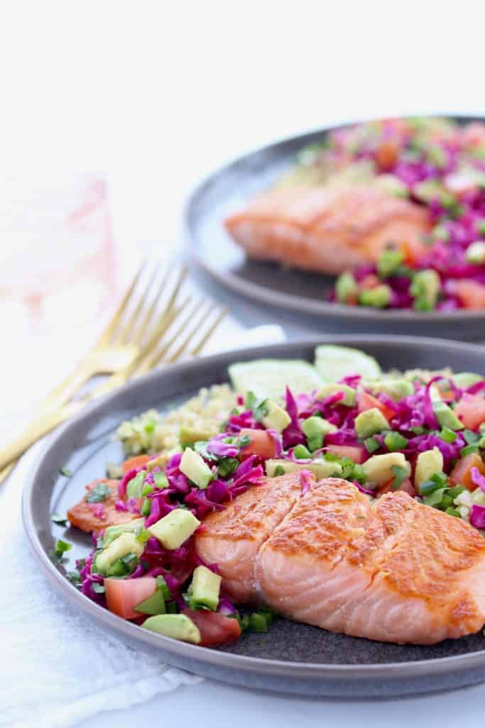 Salmon, quinoa and fresh vegetables on grey plate.