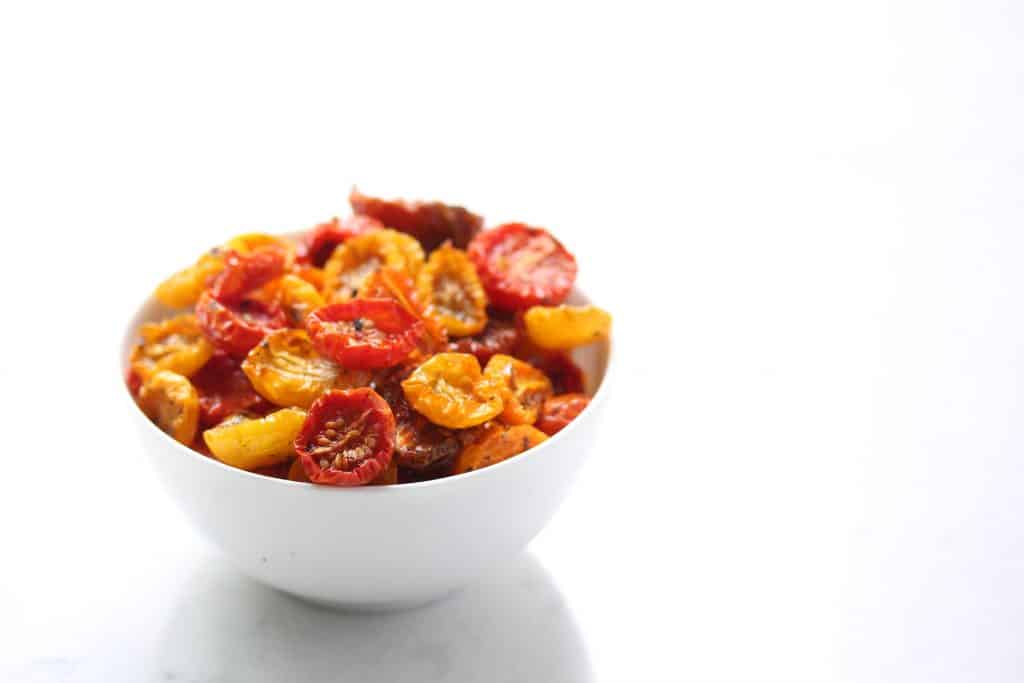 Slow roasted cherry tomatoes in white bowl.